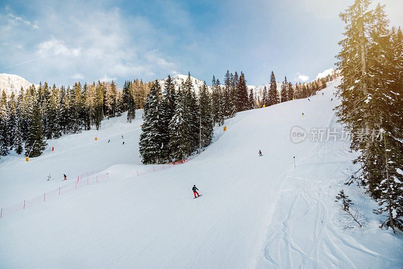 高山冬季景观与滑雪斜坡和滑雪者在一个阳光明媚的日子背景照片。阿尔卑斯山美丽的山景。冬季运动/冬季概念。自然的壁纸。